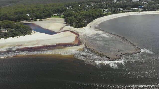 Drone video of Moona Moona Creek and Huskisson beach area after recent flooding with brown dirty water flowing into the bay