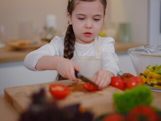 Young Girl Vlogger Making Social Media Video About Cooking At Home, looking on smartphone on tripod. episode about healthy eating. concept of attraction children to healthy diet of early age