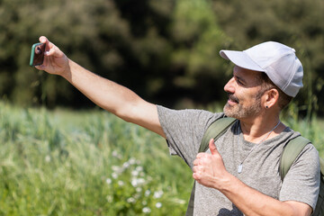 Happy smiling man in cereal field taking selfie with cell phone.