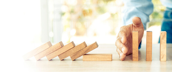 Close-up hand prevent wooden block not falling domino concepts of financial risk management and...
