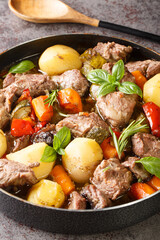 Delicious Croatian peka cooked from veal meat with seasonal vegetables and herbs close-up on the table. vertical