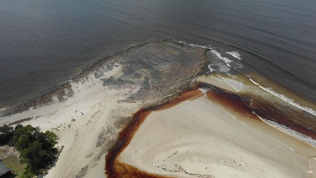 Drone video of Moona Moona Creek and Huskisson beach area after recent flooding with brown dirty water flowing into the bay
