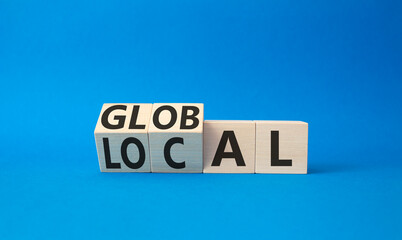 Global amd Local symbol. Turned wooden cubes with words Global amd Local. Beautiful blue background. Business and Global amd Local concept. Copy space