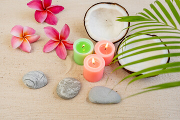 Burning candles against coconut and frangipani flowers background.