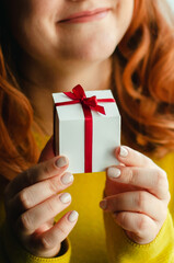 woman a red-haired girl in a yellow sweater, jacket holds a white gift box in her hands and thinks about it, portrait, gifts to relatives and friends, holidays, reflection, autumn, winter