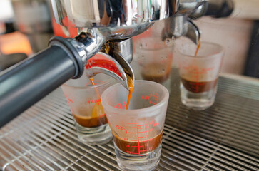 Espresso from a coffee machine pouring into a white cup of coffee.
