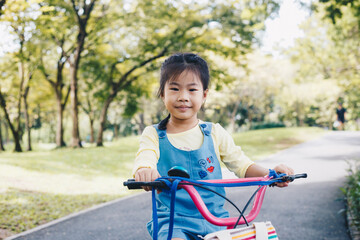 Fototapeta na wymiar Asian kid girl ride bike in tree park