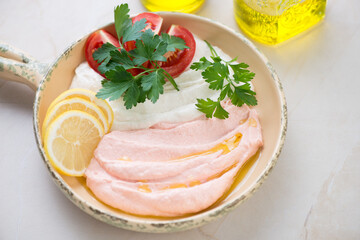 Serving pan with two types of greek tarama dip with lemon, tomatoes and fresh parsley, middle close-up on a beige stone background