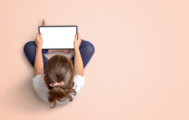 Girl holding tablet with isolated display for mockup. View from above. Copy space beside