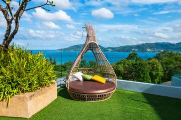 Rattan chairon hotel roof top with view of Andaman sea, Phuket