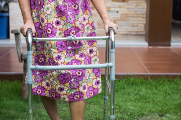 Old woman walk by walking frame after knee replacement