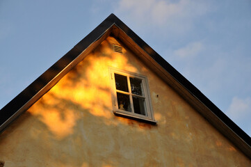 Old yellow house with roofline against blue sky
