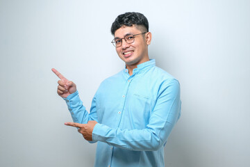 Young asian chinese man Surprised pointing with hand finger to the side, open mouth amazed...