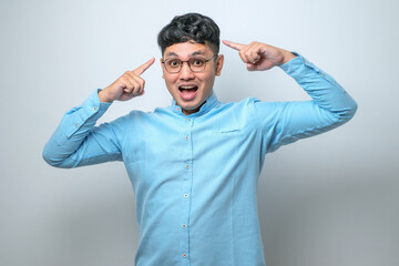 Fototapeta premium Handsome young man wearing casual shirt smiling pointing to head with both hands finger, great idea or thought