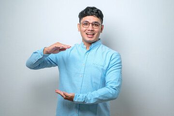 Handsome asian man gesturing with hands showing big and large size sign, measure symbol. smiling looking at the camera. measuring concept.