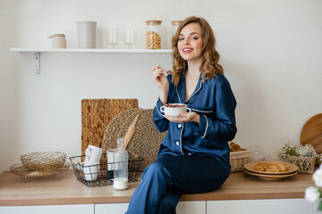 Beautiful girl in pajamas eating cereal in the kitchen