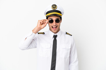Airplane pilot over isolated white background with glasses and surprised