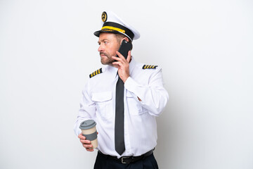 Airplane middle age pilot isolated on white background holding coffee to take away and a mobile