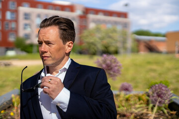 A handsome businessman in a casual dark blue suit in front of a residential area