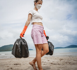 A female ecologist volunteer cleans the beach on the seashore from plastic and other waste