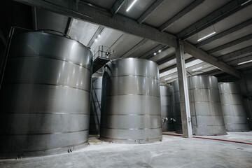 Huge warehouse for wine storing with giant stainless steel tanks. Industrial production of alcohol...