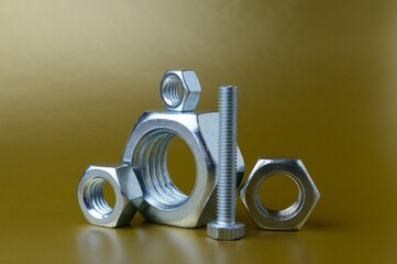 composition of new nuts and bolts of different sizes on a yellow background