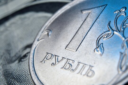 a coin with a face value of 1 ruble lies on a banknote of the American dollar. close-up