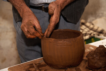 Artisan hands shaping moulding clay pot with raw clay material. Closeup of male ceramist practicing...