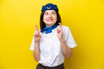 Airplane stewardess Russian woman isolated on yellow background with fingers crossing