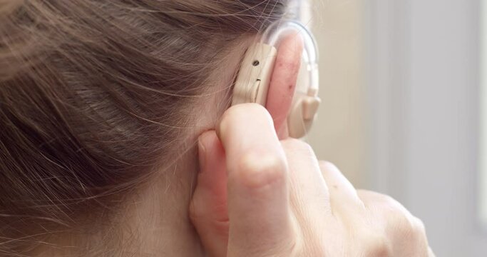 The woman turns on her hearing aid.