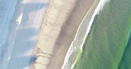 aerial video of a beach in the morning, calm swell