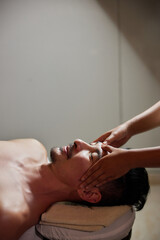 Face massage. Close-up of young man getting spa massage treatment at beauty spa salon. Spa skin and...