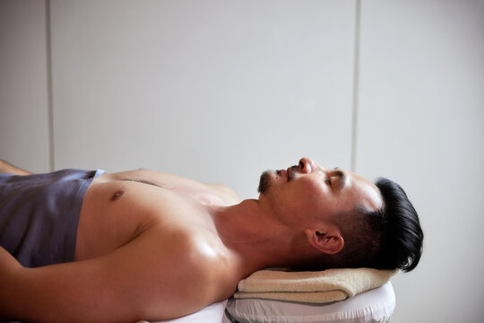 Close-up of young man lying down and waiting for spa massage treatment at beauty spa salon. Spa skin and body care. Facial beauty treatment. Cosmetology.