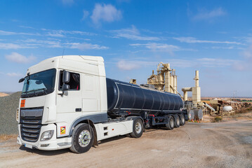 Tanker truck loaded with high temperature bitumen entering an agglomerated asphalt manufacturing...
