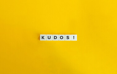 Kudos Word on Block Letter Tiles on Yellow Background. Minimal Aesthetics.