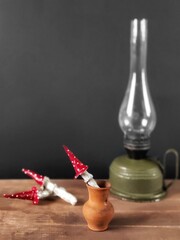 Rustic retro kerosene lamp on a wooden table with toadstools in clay pot and copy space. Still life with a kerosene lamp and fly agarics on a black background.
