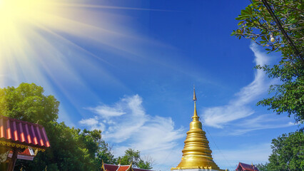 The blue sky, white clouds with sunlight shining on the golden pagoda look natural.