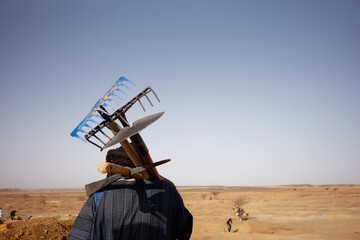 Gold artisanal miner carrying rakes and shovel in the Inchiri desert, Mauritania.