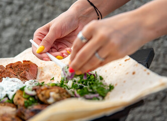 woman hand holding plastic fork with meat and sause outdoor