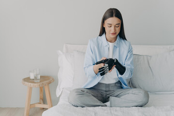Attractive european girl adjusting her cyber arm at home. Artificial hand and arm with wrist joint.