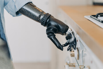Electronic cyber hand of disabled person is switching a stove. Sensor in fingers and wrist joint.