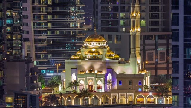Dubai Marina skyline with Mohammad Bin Ahmed Al Mulla mosque aerial timelapse at night. Skyscrapers with glowing windows on a background close up view
