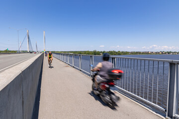 Piste cyclable du pont de l'autoroute 25 avec un scooter électrique dans un sens et vélo dans...