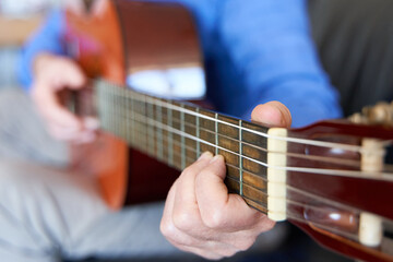 Fototapeta na wymiar Mature male fingers in fretboard of classical guitar