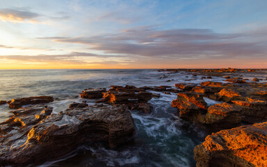 Obraz premium Sunrise view at the rocky beach coastline.