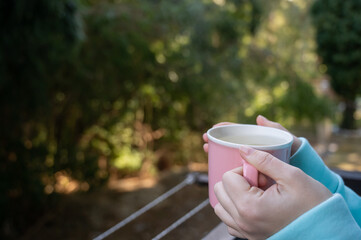 Woman drinking hot drink standing on the balcony. 