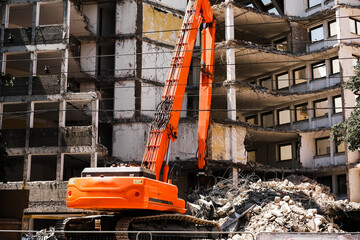 excavator collects the remains of bricks and concrete slabs of the destroyed building