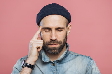 Headshot of serious thoughtful middle aged man tries to remember something in his mind, keeps fore...