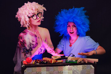 Happy women in funny wigs give a musical performance on a studio black background. Smiling women...