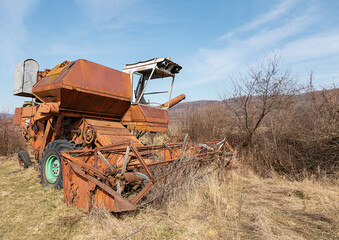 selective focus on old abandoned combine harvester for grain crops in the field. Broken rusty...